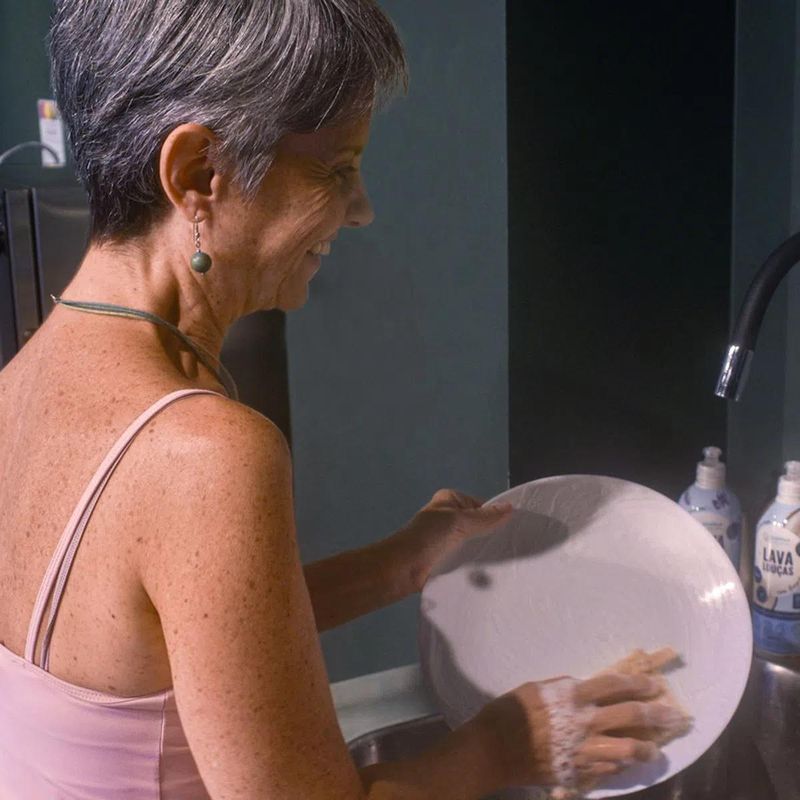 pessoa lavando um prato na pia, usando a bucha vegetal da positiv.a e o detergente lava louças lavanda da positiv.a